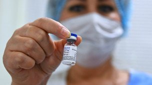 Медицинская работница демонстрирует флакон с вакциной