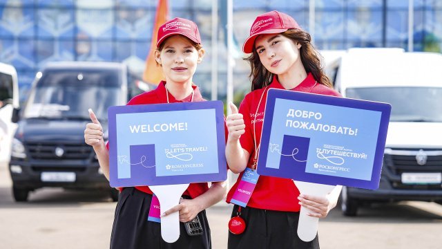 devushki-volontery-s-privetstvennymi-tablichkami-na-forume-puteshestvuj