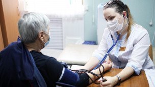 Врач измеряет тонометром давление пациентке