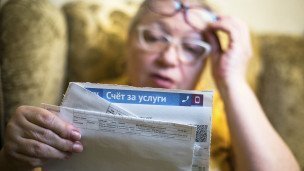 женщина держит в руках счет за услуги жкх