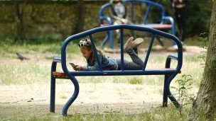 девочка с телефоном на скамейке в парке