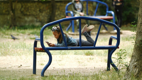 девочка с телефоном на скамейке в парке