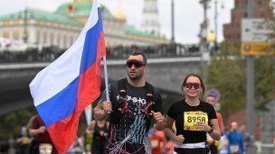 Участники на дистанции марафона с российским флагом в руках