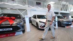 Покупатель проходит между автомобилями в автосалоне 