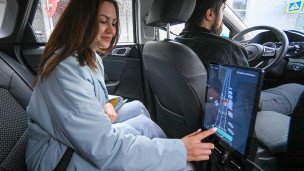 Пассажирка в салоне автомобиля выбирает маршрут по навигатору