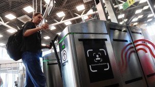 Женщина проходит через турникет с новой системой для оплаты проезда по биометрии Face Pay