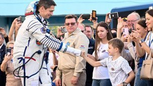 Космонавт приветствует толпу радостных людей 