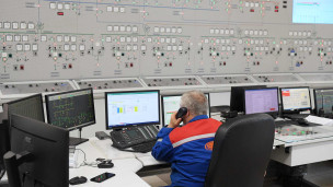 Сотрудник за центральным пультом управления гидроэлектростанции