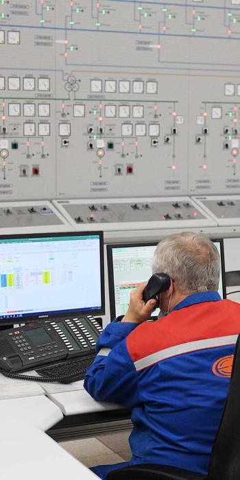 Сотрудник за центральным пультом управления гидроэлектростанции
