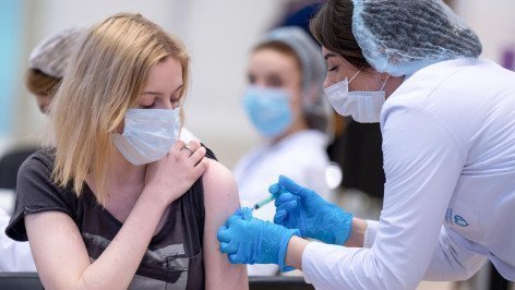 Медицинский работник делает девушке прививку от COVID-19