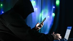 Мужчина в капюшоне с телефоном в руке