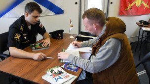 В мобильном пункте отбора на военную службу по контракту мужчина подписывает контракт