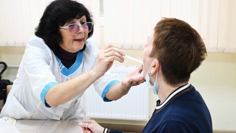 Врач смотрит горло у пациента 