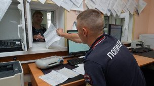 Сотрудник отделения полиции передает документы 