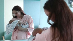 Женщина с новорожденным ребенком в родильном доме