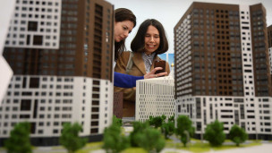 Девушки с телефоном около макета дома