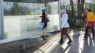 Пассажиры у теплой остановки общественного транспорта 