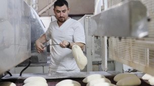 Работник во время производства хлебобулочных изделий
