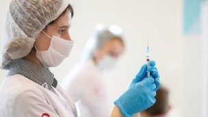 Шприц с вакциной в руках медика