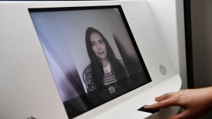 Девушка фотографируется и прикладывает палец для биометрического профиля
