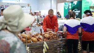 Продавец за мясным прилавком рядом посетители выставки