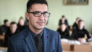 Школьный учитель во время урока на заднем плане ученики за партами