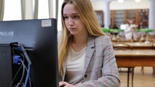 Студентка за компьютером во время подготовки в читальном зале