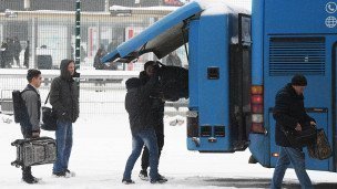 Пассажиры загружают вещи в автобус на автовокзале 
