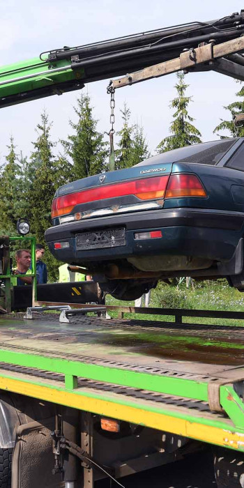 эвакуатор во время погрузки автомобиля для утилизации