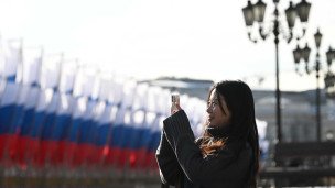 Туристка фотографирует праздничные флаги в России