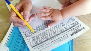 Женщина с ребенком заполняет квитанции на оплату коммунальных услуг