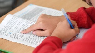 Крупный план ученик читает учебник и записывает
