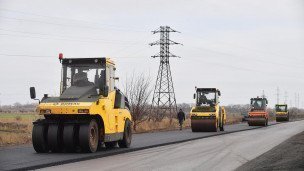 Сотрудники дорожно-строительной компании ремонтируют дорогу