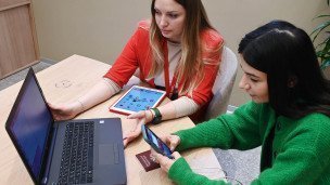 Две девушки за ноутбуком одна с планшетом другая с телефоном