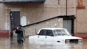 Мужчина стоит рядом с машиной на подтопленной улице