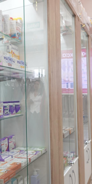 Покупательница рассматривает лекарственные препараты на витрине