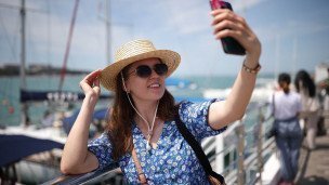 Девушка на набережной делает селфи на фоне моря