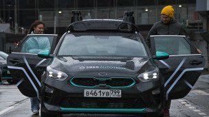 Пассажиры садятся в салон беспилотного автомобиля Sberautotech в Москве
