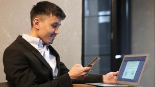 Мужчина с ноутбуком и смартфоном в деловом костюме