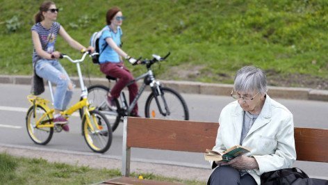 Пожилая женщина читает книгу в парке