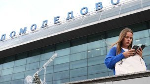 Девушка с телефоном около аэропорта