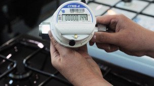 Продавец-консультант держит в руках газовый счетчик