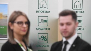 Сотрудники банка на переднем плане на заднем надпись ипотека кредиты вклады