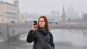 девушка с телефоном во время прогулки по москве