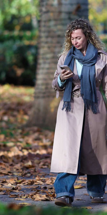 Девушка со смартфоном гуляет в парке