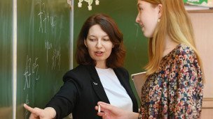 Преподаватель и ученица у школьной доски 