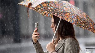 Devushka-vo-vremya-dozhdya-s-zontom-i-telefonom