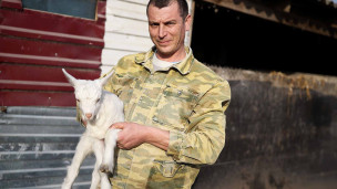 мужчина держит козленка в руках