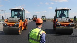 dva-katka-i-rabotnik-dorozhnoj-sluzhby-vo-vremya-ukladki-asfalta
