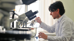 Мужчина за микроскопом в лаборатории 